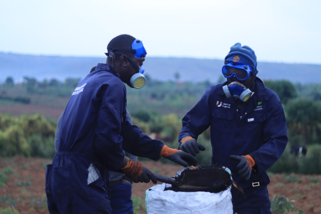 Zwei Flüchtlinge füllen hochwertigen Biochar in einen Sack. So wurde CO2 aus der Luft gebunden.