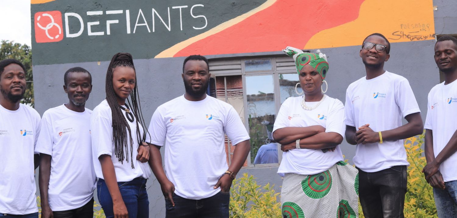 Unidos team, Nakivale Refugee Settlement, Uganda, seven people standing in front of building with lettering DEFIANTS