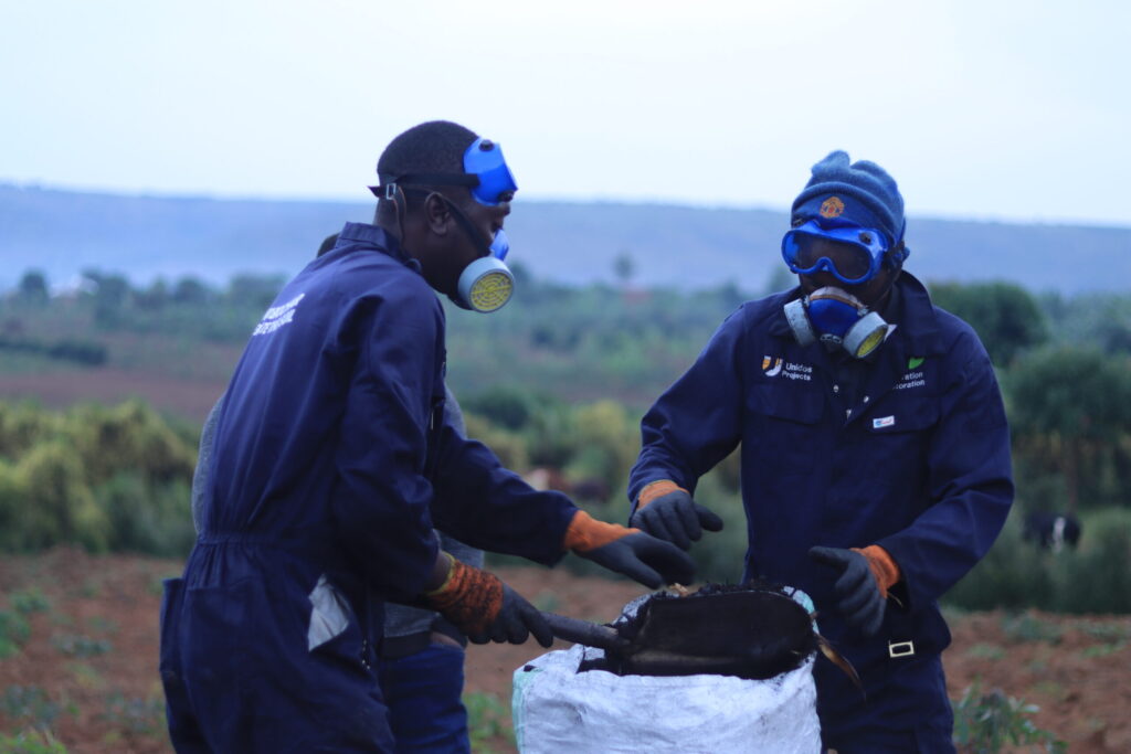 Two refugees fill high-quality biochar into a sack, helping to capture and store carbon from the atmosphere.